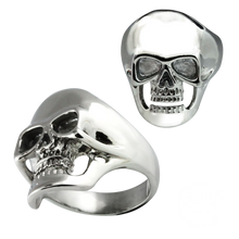 Load image into Gallery viewer, A stainless steel skull ring shown from two angles on a plain white background, with one view showing the front of the skull and the other showing the side and band.
